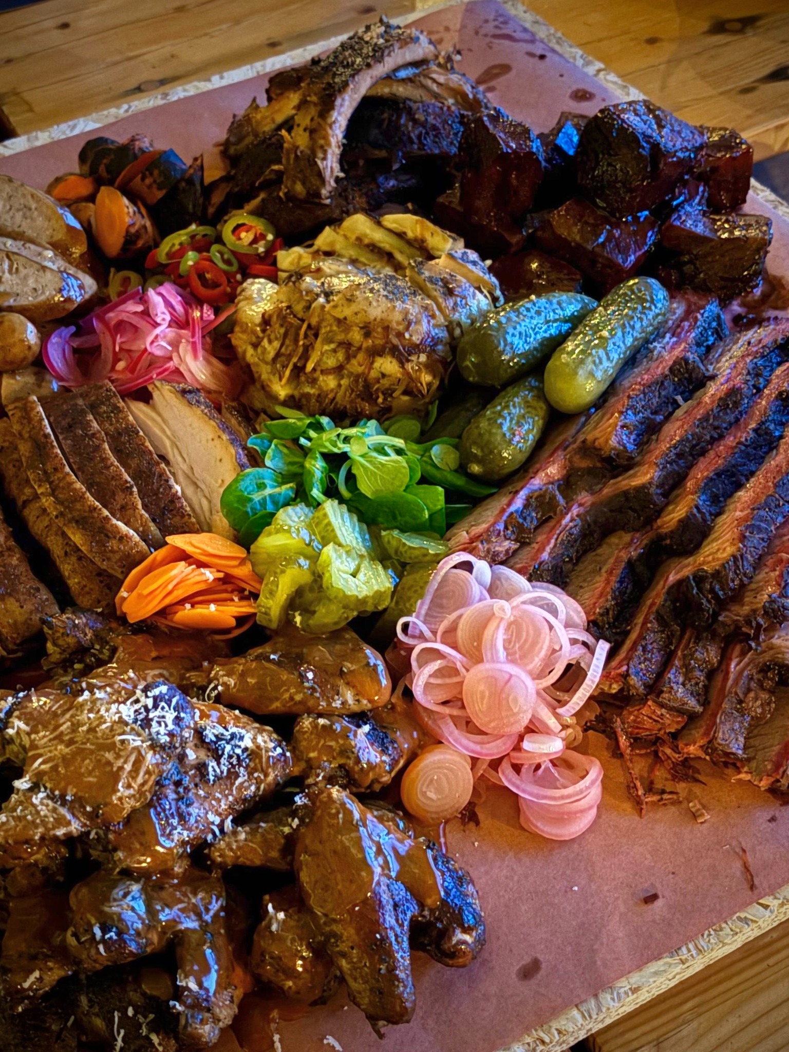 Generous barbecue platter with sliced meats, chicken, pickles and sides